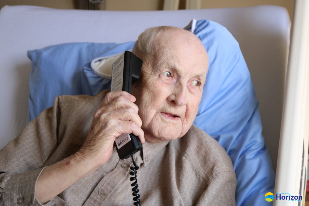 Photo of patient with visitors coming to his hospital bed's window